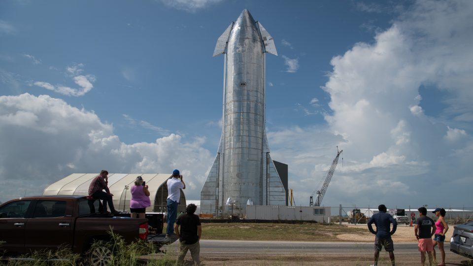 FILE: Space enthusiasts look at a prototype of SpaceX’s Starship spacecraft at the company’s Texas launch facility on September 28, 2019 in Boca Chica near Brownsville, Texas. The Starship spacecraft is a massive vehicle meant to take people to the Moon, Mars, and beyond.