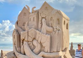Sand sculpture of a building being attacked by a tentacled creature