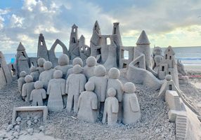 Sand sculpture of buildings and a crowd of people